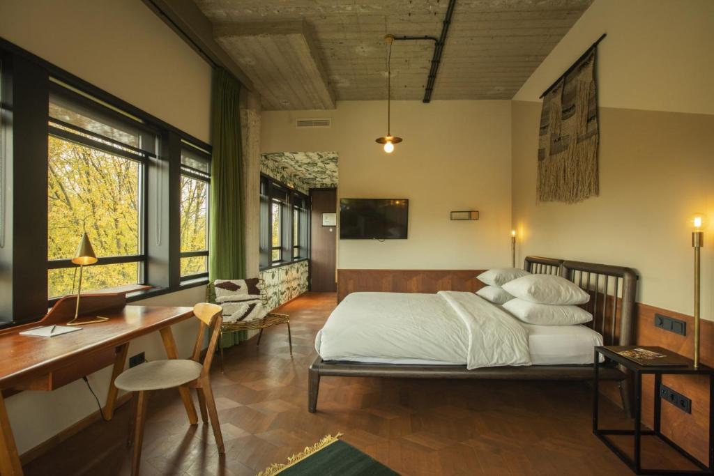 Schlafzimmer mit einem Bett, einem Schreibtisch und Fenstern in der Unterkunft Hotel V Fizeaustraat in Amsterdam