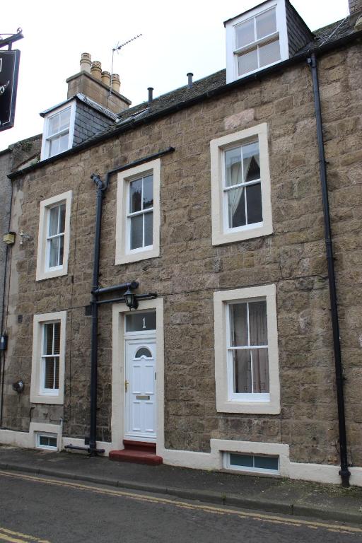 un edificio de ladrillo con una puerta y ventanas blancas en Number One, en Haddington