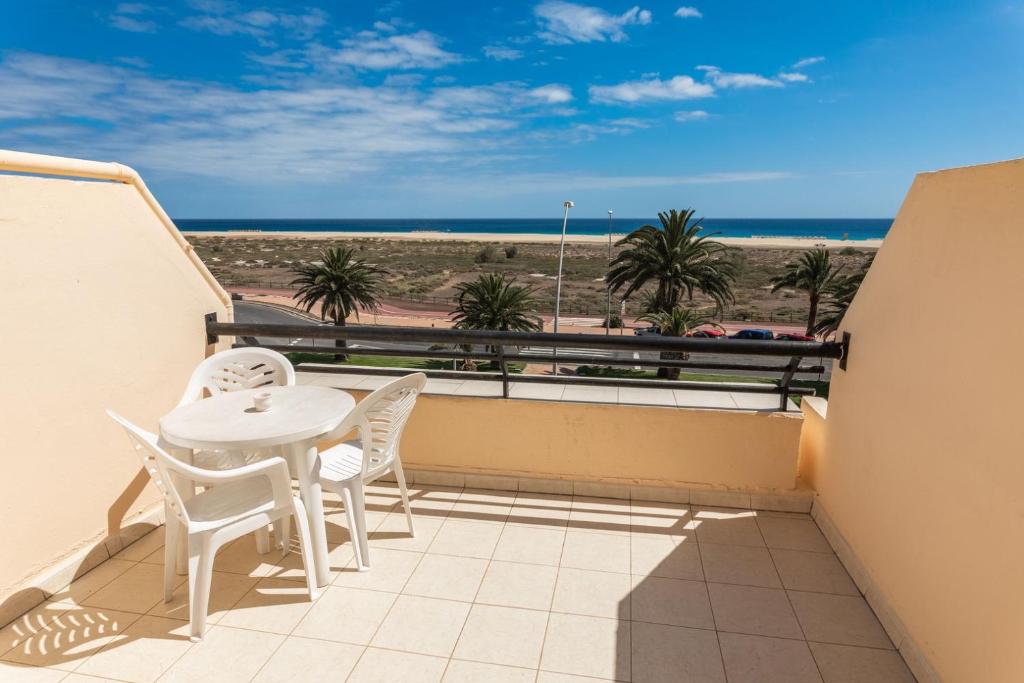 a balcony with a table and chairs and the beach at Palm Garden in Morro del Jable