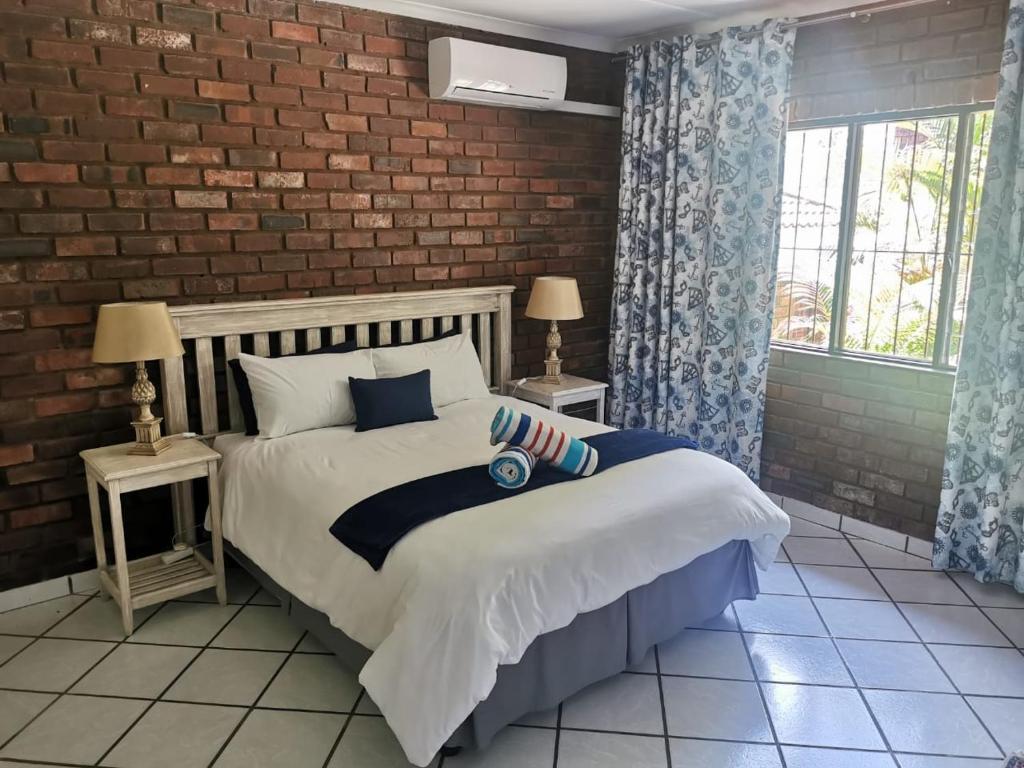 a bedroom with a bed and a brick wall at The Dunes in St Lucia