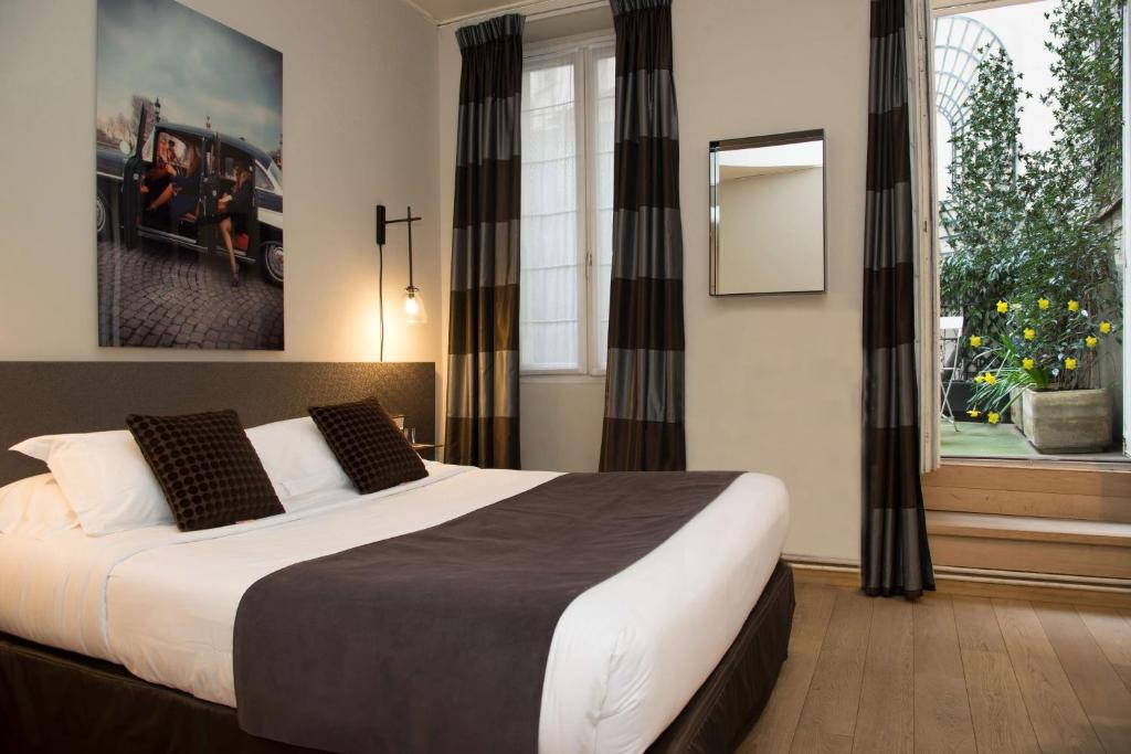 a bedroom with a large bed and a painting on the wall at Tilsitt Etoile in Paris