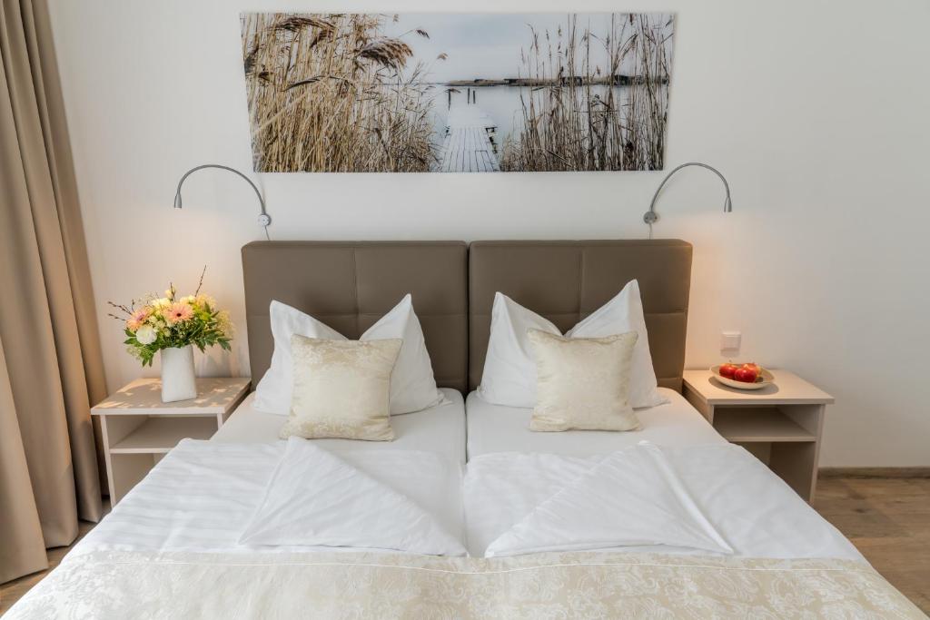Schlafzimmer mit einem Bett mit weißer Bettwäsche und Kissen in der Unterkunft Hotel Wende in Neusiedl am See