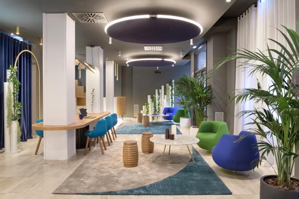 a lobby with blue and green chairs and tables at Hotel Inca in Zaragoza
