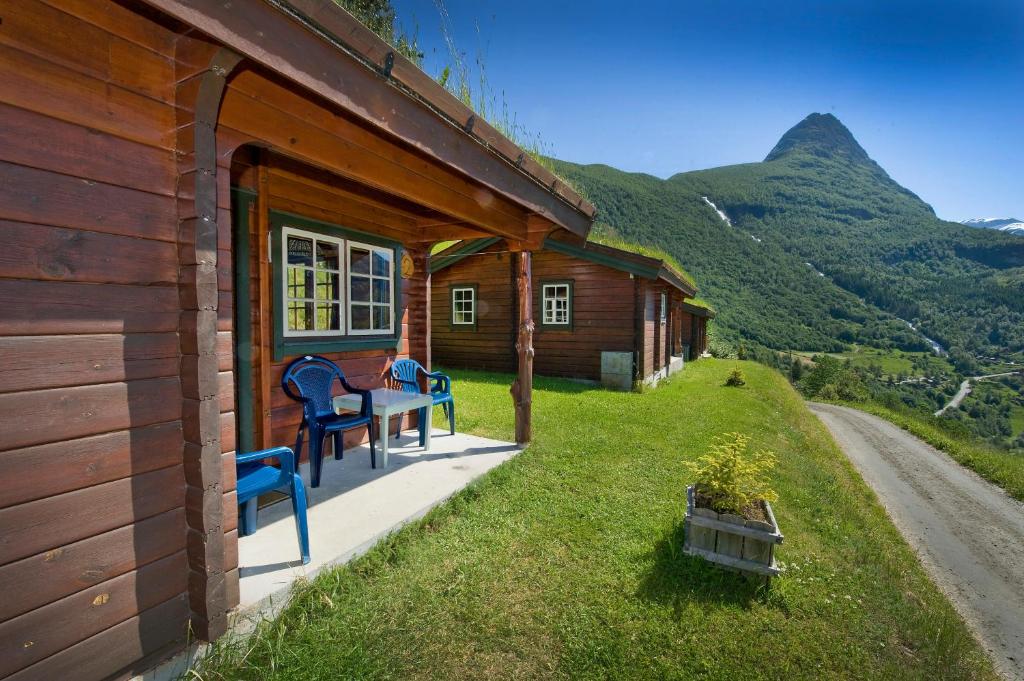 eine Hütte mit einem Tisch und Stühlen auf der Veranda in der Unterkunft Westerås Gard in Geiranger