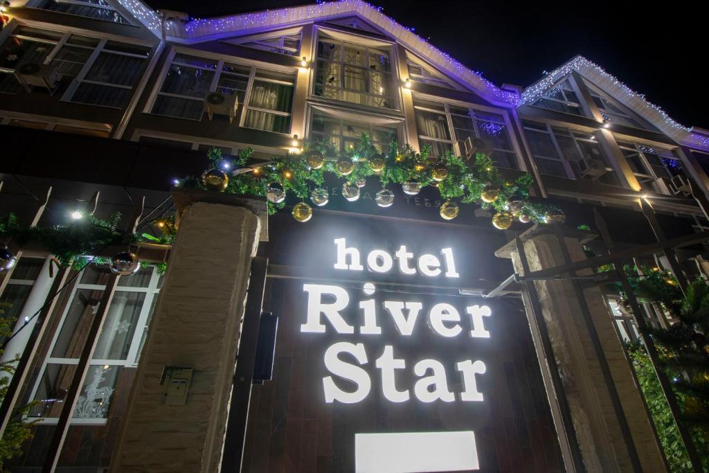 a hotel river star sign in front of a building at night at River Star Hotel in Adler