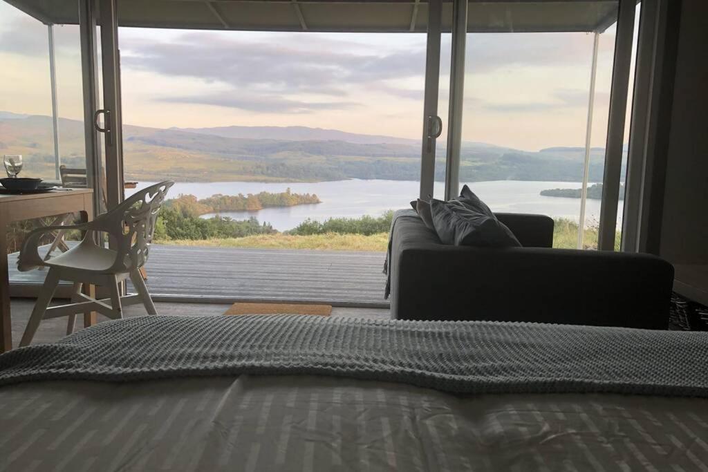 a bedroom with a large window with a view of a lake at Columba Lodge, St Conan's Escape, Idyllic highland getaway in Dalmally