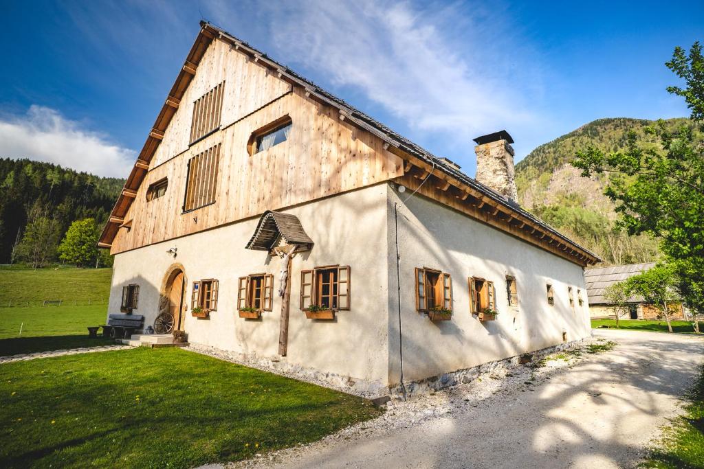 a large white building with windows and a mountain at Tourist Farm Šenkova Domačija in Zgornje Jezersko