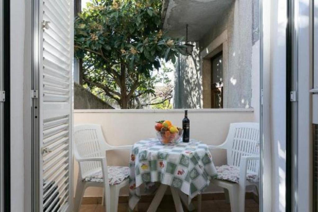 - une table avec une bouteille de vin et des fleurs sur le balcon dans l'établissement Apartment Anita, à Dubrovnik