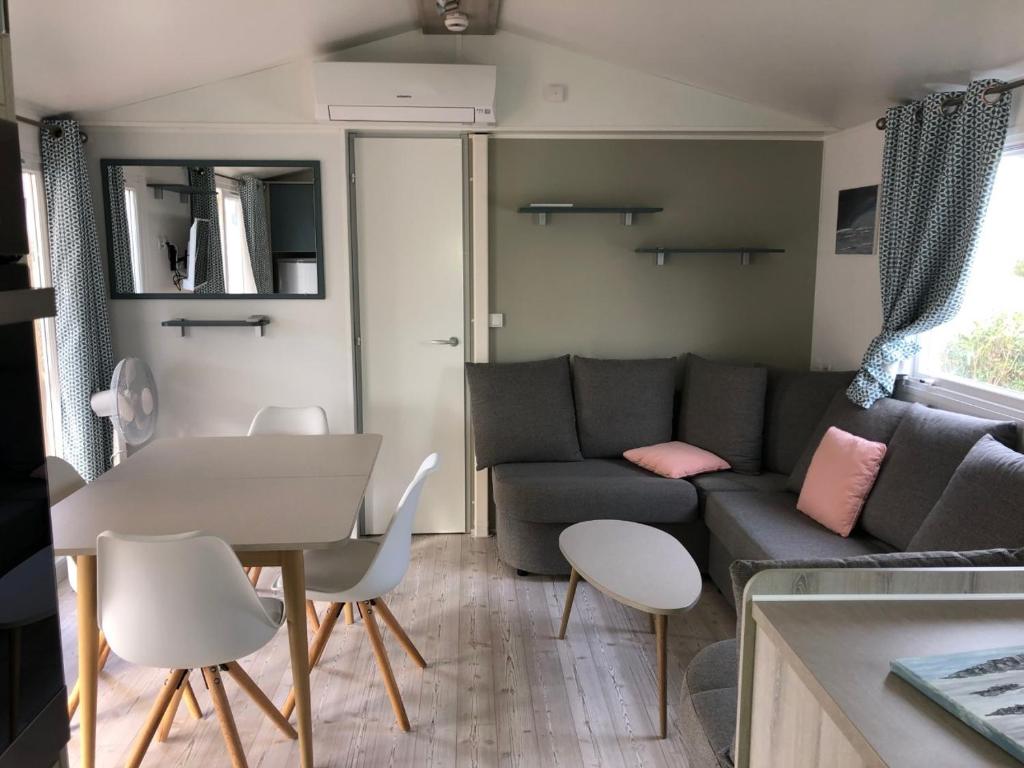 uma sala de estar com um sofá, uma mesa e cadeiras em Mobil Home Valras Plage em Valras-Plage