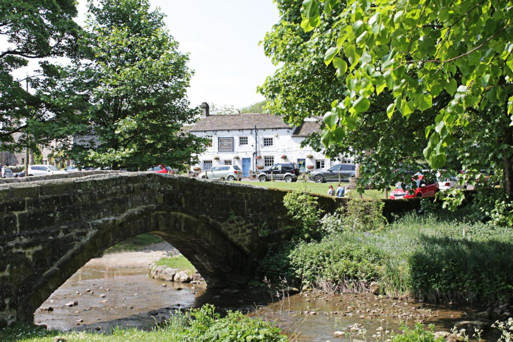 eine alte Steinbrücke über einen Fluss in einer Stadt in der Unterkunft The Fountaine Inn in Linton