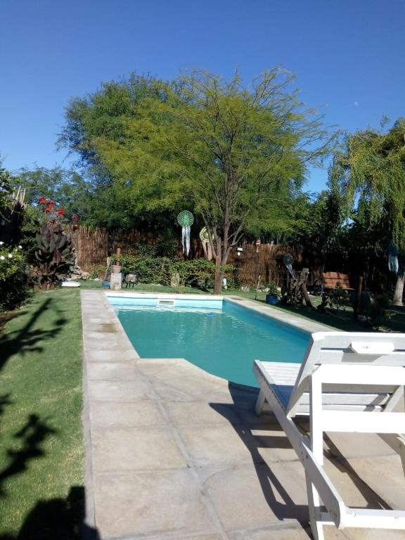 a swimming pool with two white chairs next to it at El Indio - Casa de Campo con Piscina y Parrilla in Villa del Salvador