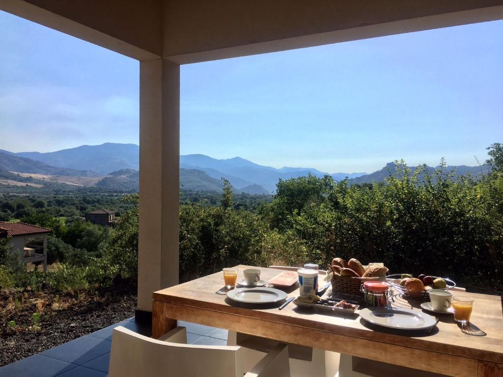 - une table avec des assiettes de nourriture sur un balcon avec des montagnes dans l'établissement Tenuta Madonnina, à Castiglione di Sicilia