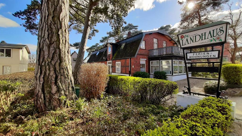 una señal frente a un edificio con un árbol en Landhaus Voß, en Timmendorfer Strand