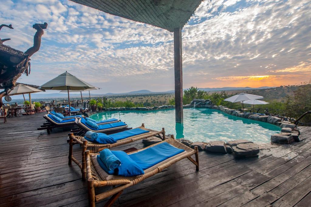 un grupo de tumbonas sentadas en una terraza junto a una piscina en Mbalageti Serengeti, en Parque Nacional del Serengeti