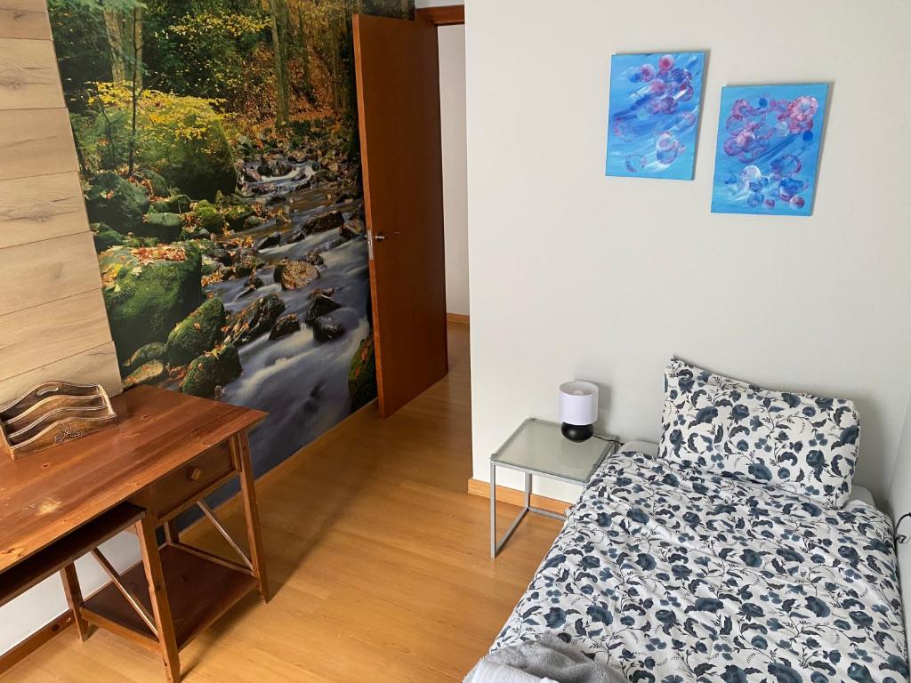 Dormitorio con cama, escritorio y pintura en Dúplex Roca del Sucut, en Ribes de Freser