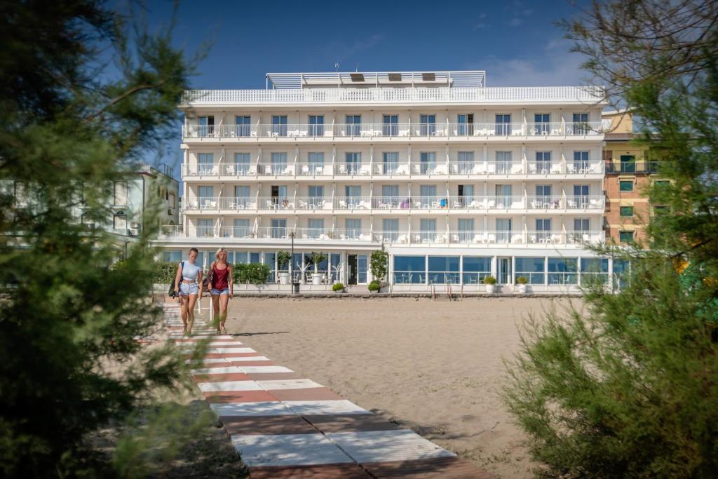 two people walking on the beach in front of a hotel at Stellamare in Caorle