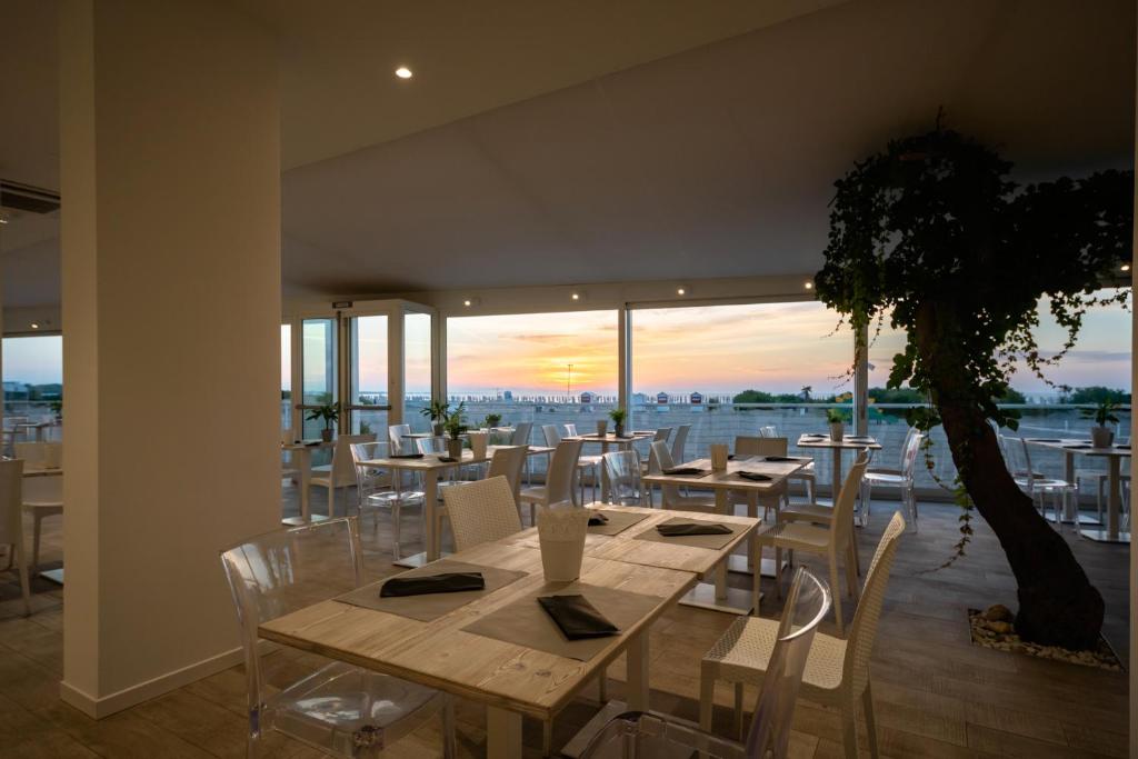a dining room with tables and chairs and a tree at Stellamare in Caorle