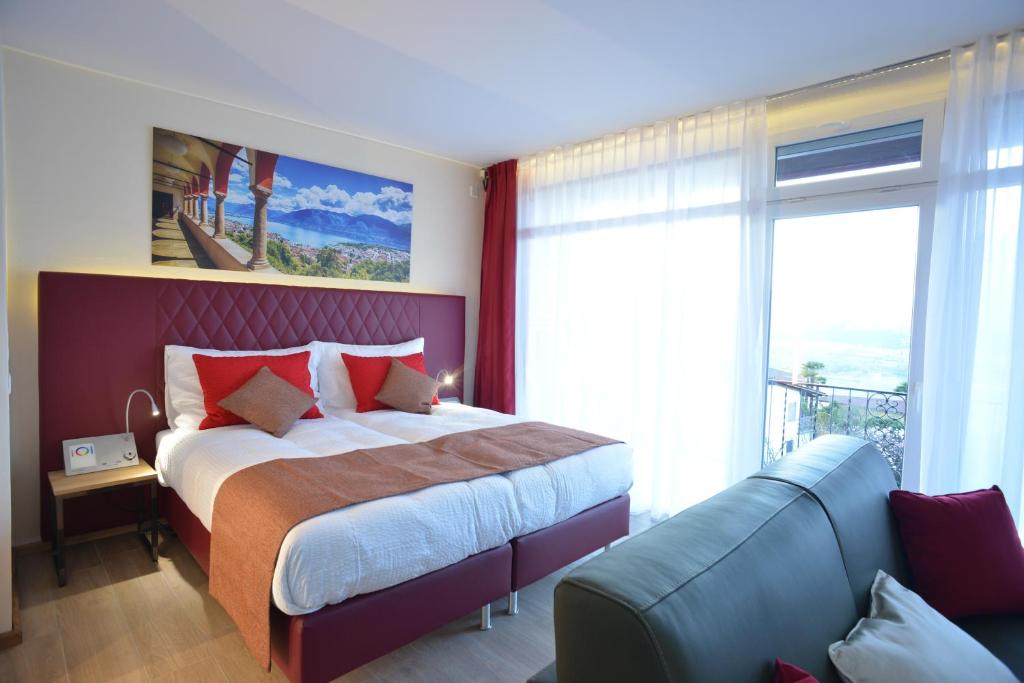 a bedroom with a large bed and a couch at La Campagnola - Top Swiss Family Hotel in San Nazzaro