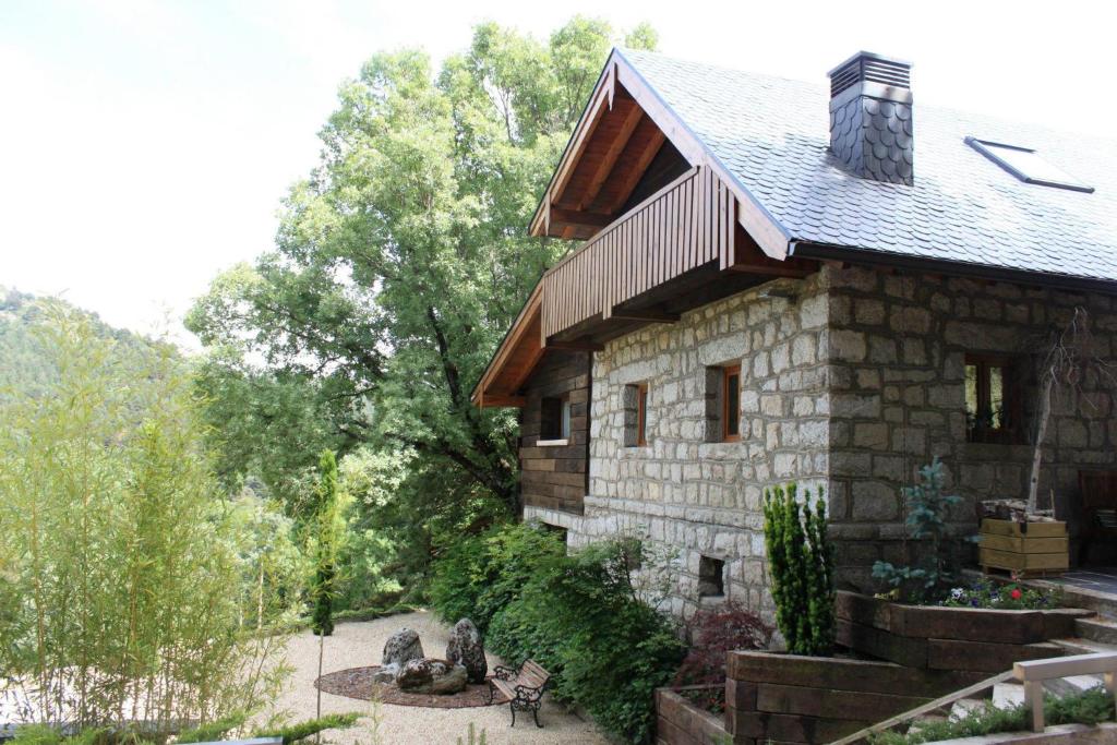 une maison en pierre avec un jardin en face dans l'établissement Hotel Rural Las Rozuelas, à Cercedilla