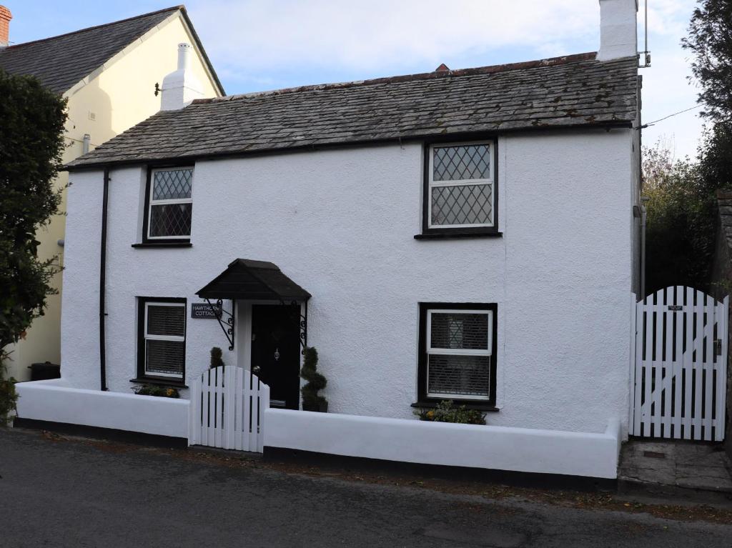 a white house with a white picket fence at Hawthorn Cottage in Bodmin