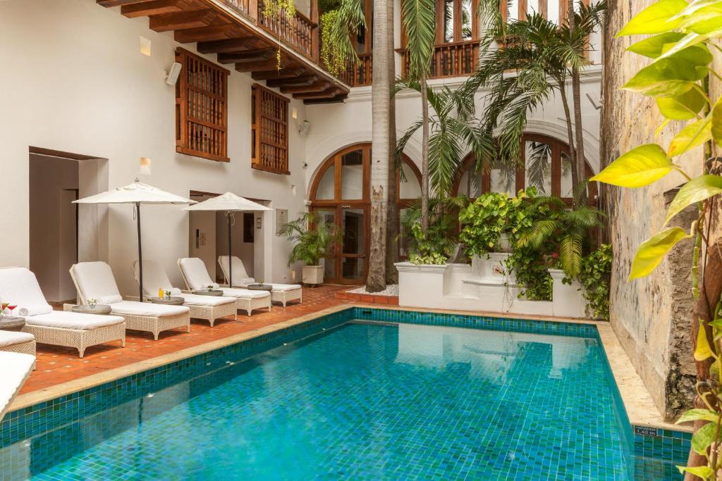 uma piscina com espreguiçadeiras e um resort em Hotel Casa San Agustin em Cartagena de Indias