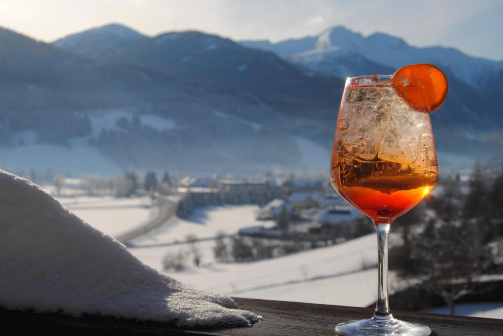 una copa de vino sentada en una mesa con una naranja en ella en Hotel Speiereck, en Sankt Michael im Lungau