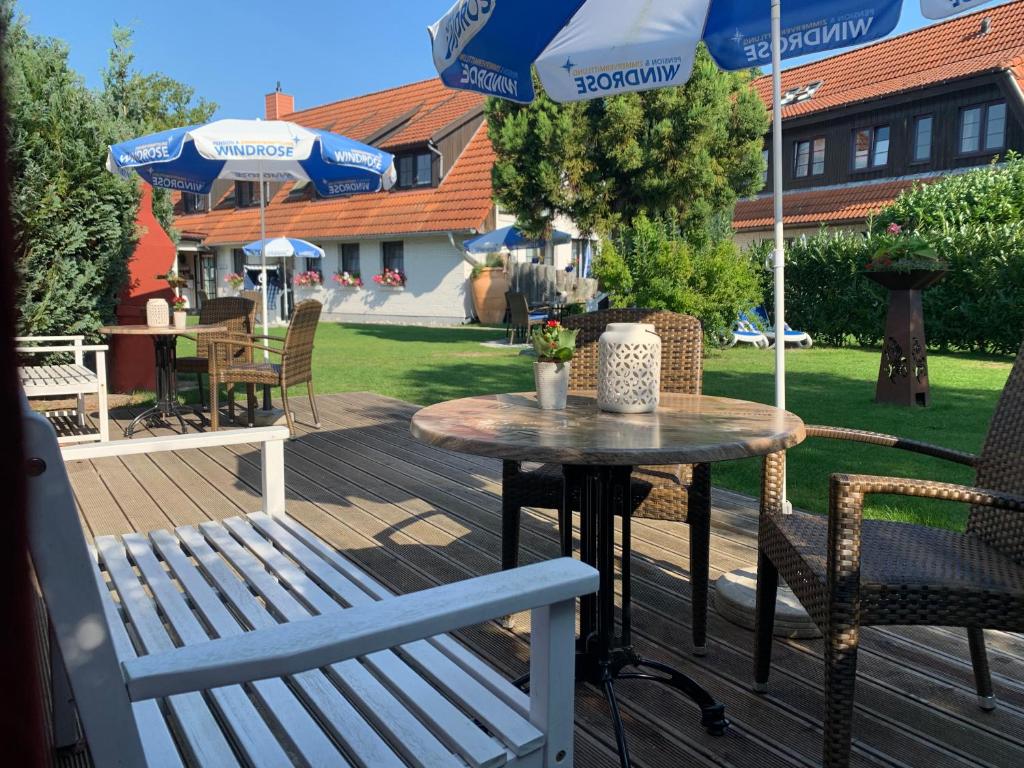 a patio with a table and chairs and umbrellas at Pension Windrose in Prerow
