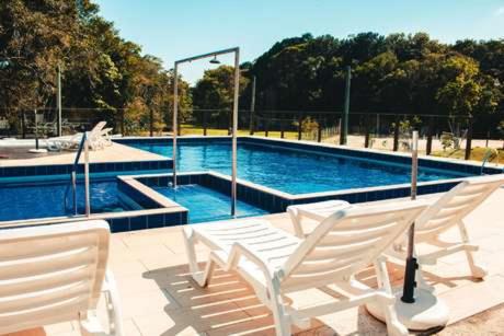 uma piscina com cadeiras brancas em frente em Palmas Hotel & Spa em Governador Celso Ramos