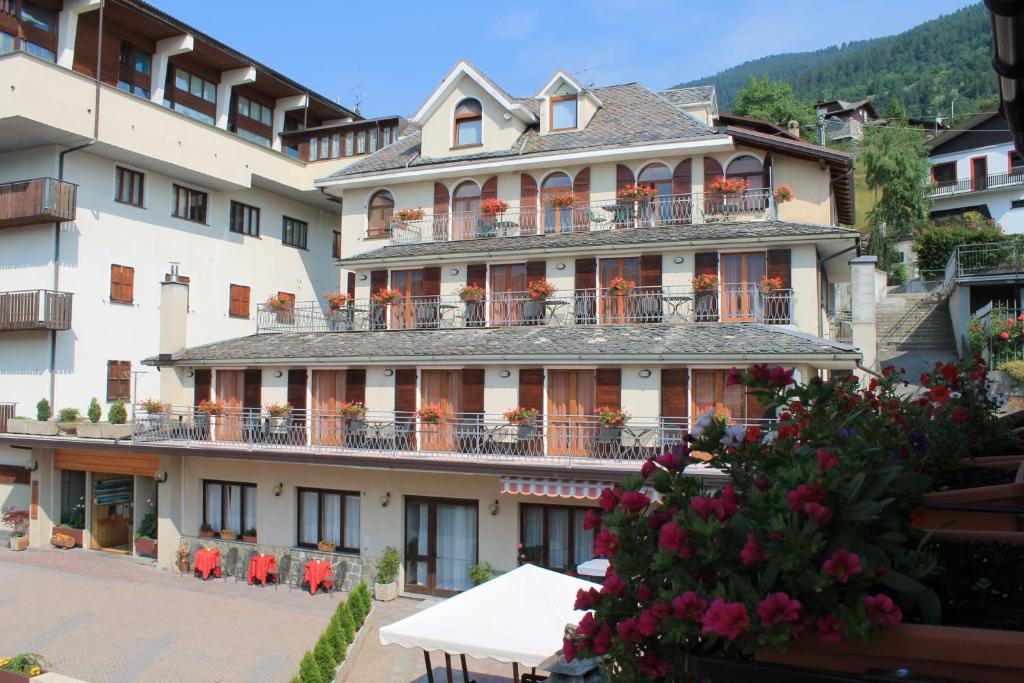 ein großes Gebäude mit Balkonen und Tischen davor in der Unterkunft Hotel La Rosa in Teglio