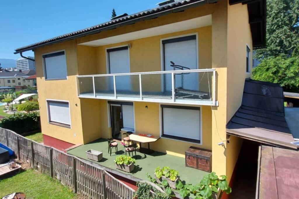 a yellow house with a balcony with a table at Quiet apartment close to town in Villach