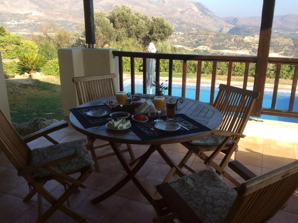 una mesa con comida y bebida en la parte superior de un balcón en Crete Family Villas, en Pentamodi