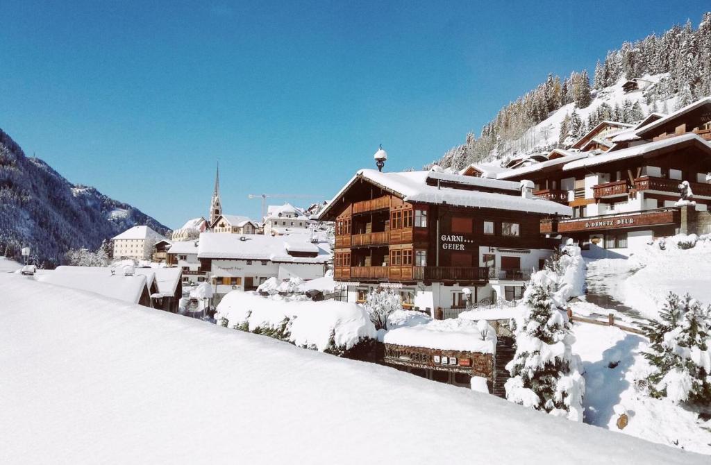 budynek pokryty śniegiem w górach w obiekcie Garni Hotel Geier w mieście Santa Cristina Valgardena