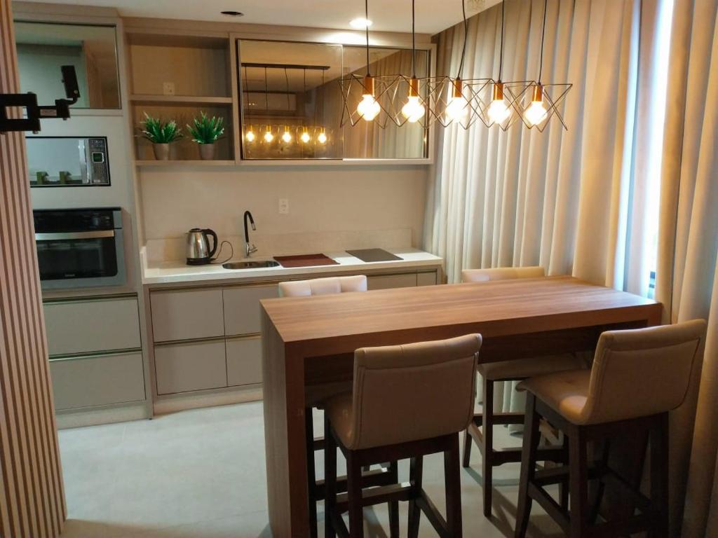 uma cozinha com uma mesa de madeira e cadeiras em Apto com vista para o mar e o farol - loft 323 em Laguna