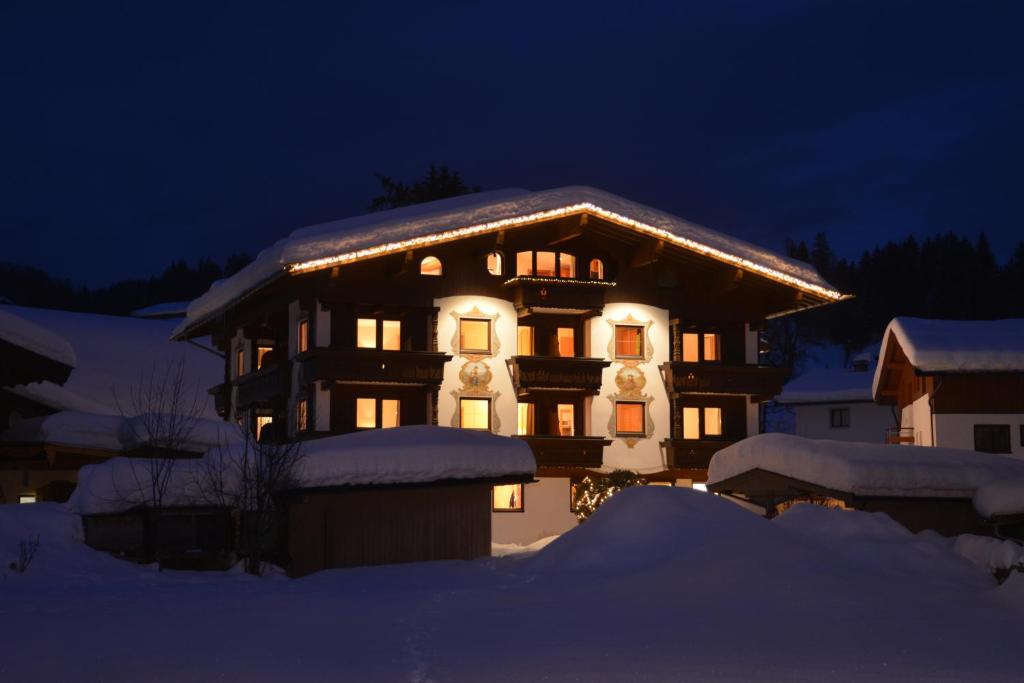 una casa con nieve en el techo por la noche en Apartments Tirolerhaus en Kössen