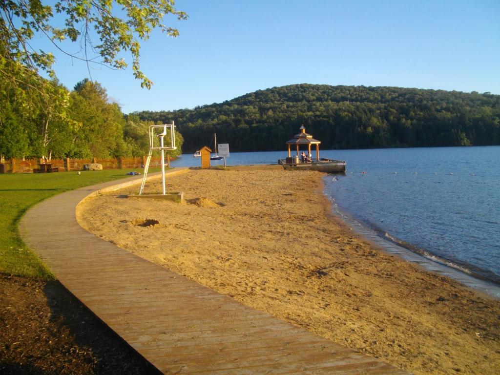 a beach with a gazebo next to a lake at Bernache in Mont-Tremblant