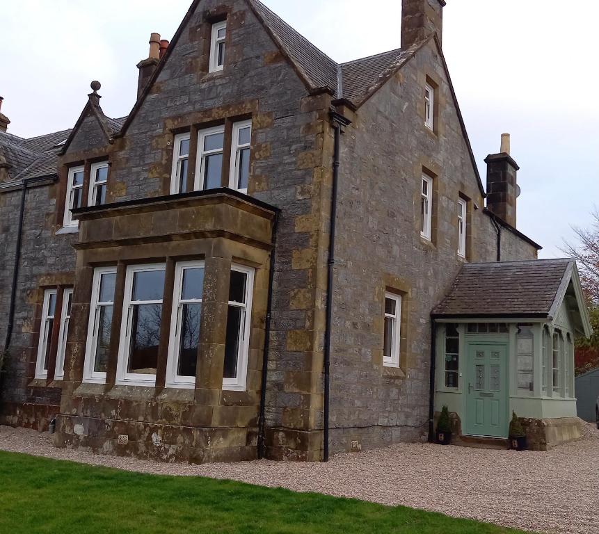 uma antiga casa de pedra com uma porta verde em Conval House Bed And Breakfast em Dufftown