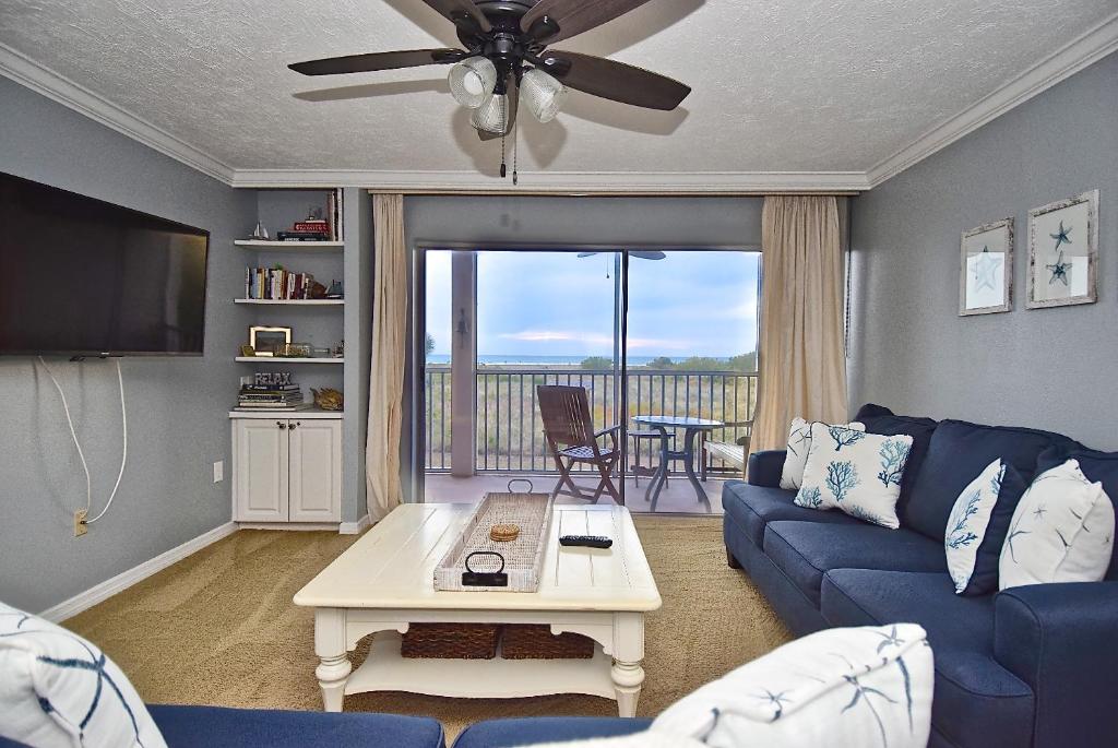 a living room with a blue couch and a table at Direct Beachfront Delight by Beachside Management in Siesta Key