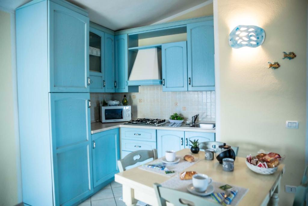 ヴァッレドーリアにあるSardinia Imagination - Valledoria M03の青いキャビネットとテーブル付きのキッチンが備わります。