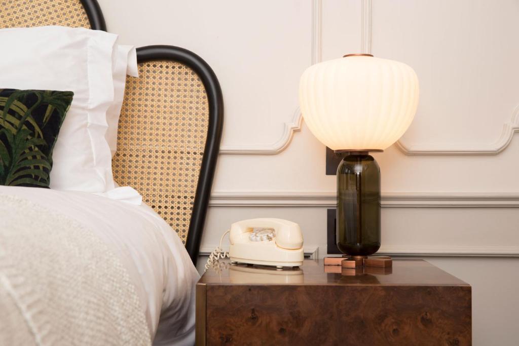 a lamp on a table next to a bed with a phone at The Hoxton, Downtown LA in Los Angeles