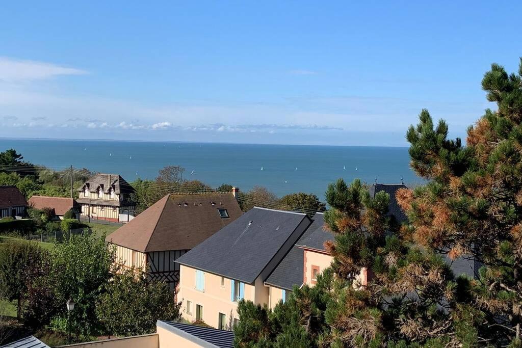 un groupe de maisons avec l'océan en arrière-plan dans l'établissement Trouville-Apt rénové-Balcon magnifique vue mer, à Trouville-sur-Mer