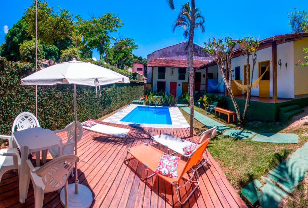 une terrasse avec des chaises et un parasol ainsi qu'une piscine dans l'établissement Pousada Aloha Arraial, à Arraial d'Ajuda