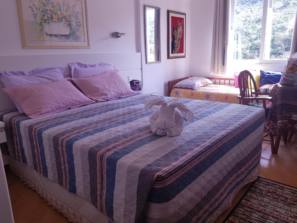 un animal de peluche sentado en una cama en un dormitorio en Hotel Cavalinho Branco Flat Service 615 en Águas de Lindóia