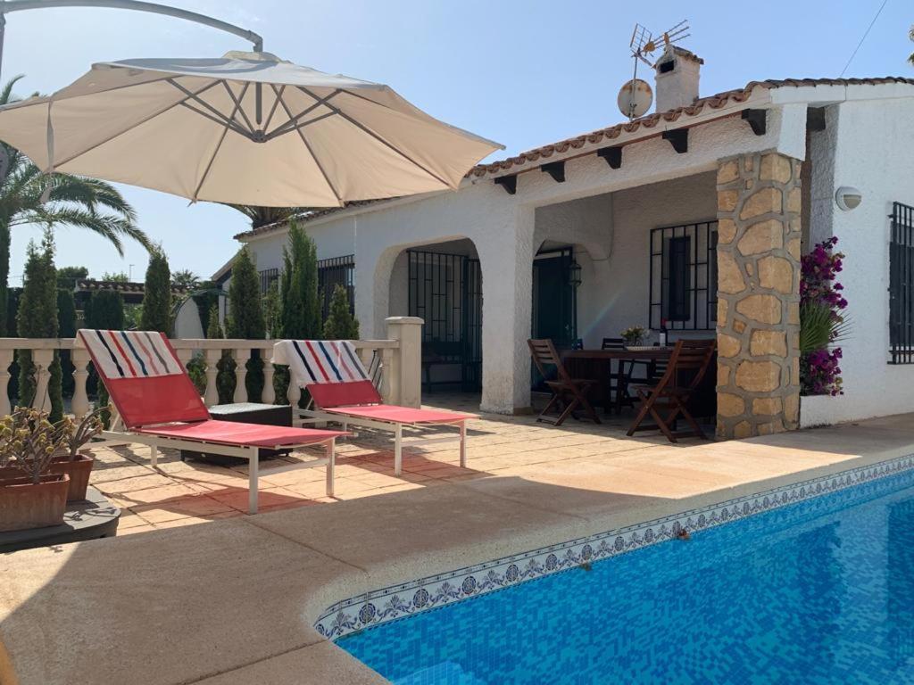 een patio met 2 stoelen en een parasol naast een zwembad bij Annette in Albir