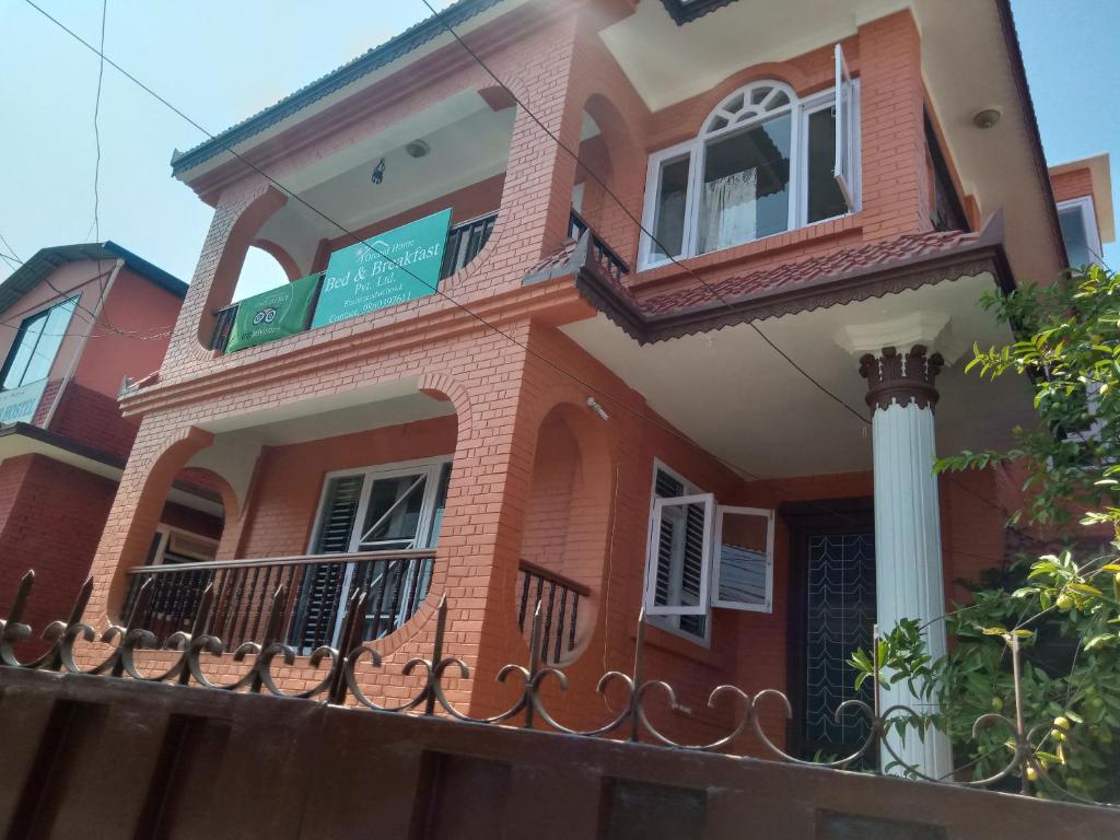 a red brick house with a balcony at Orchid Home Bed & Breakfast pvt ltd in Kathmandu