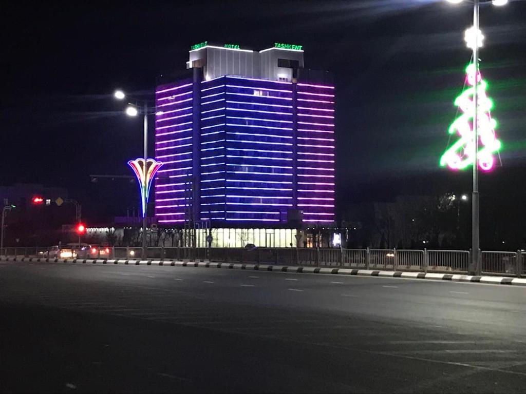 un edificio iluminado con un árbol de Navidad delante de él en Tashkent Hotel, en Nukus