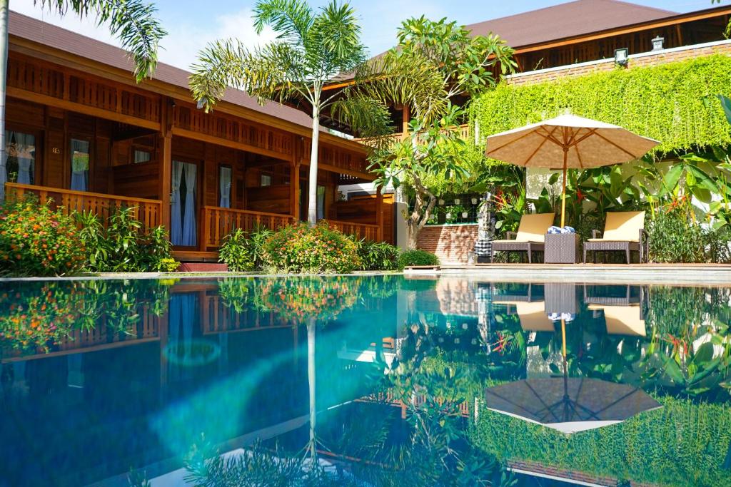 a swimming pool with an umbrella and a house at La'villaris hotel & resto in Kuta Lombok
