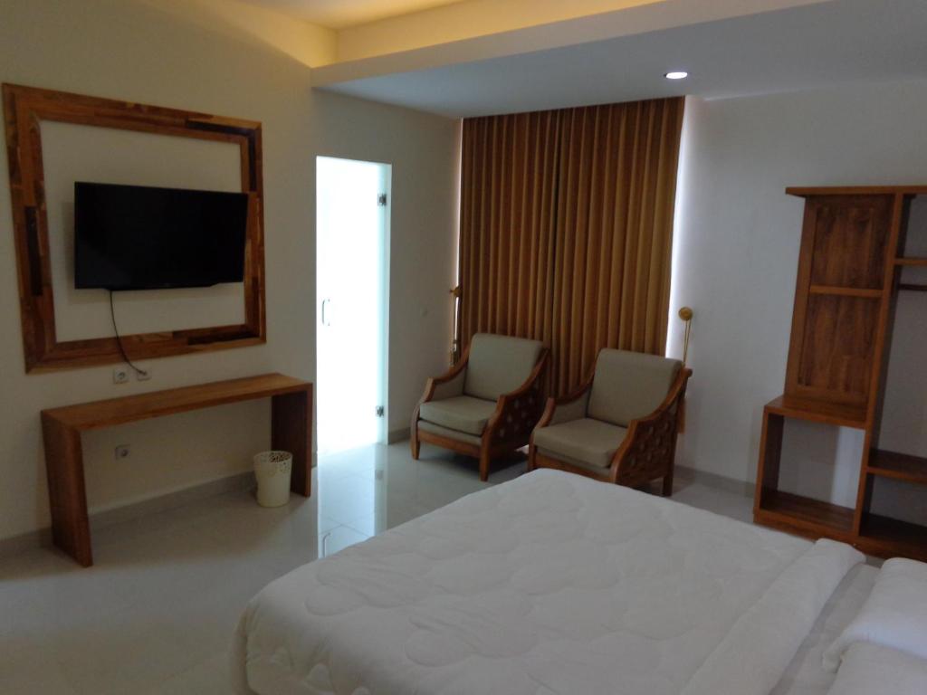 1 dormitorio con 1 cama, 2 sillas y TV en Diva Residence en Yogyakarta