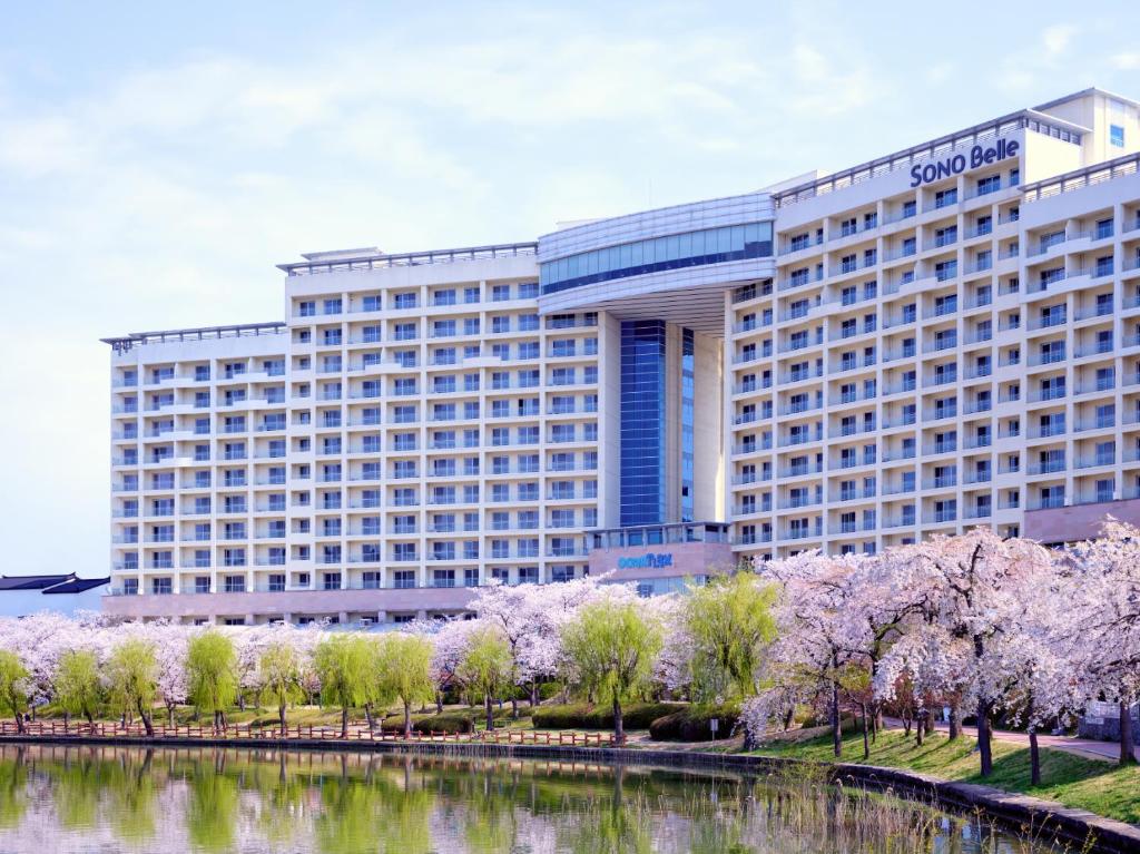 Sono Belle Gyeongju في جيونجو: فندق مع أشجار اكورا أمام النهر