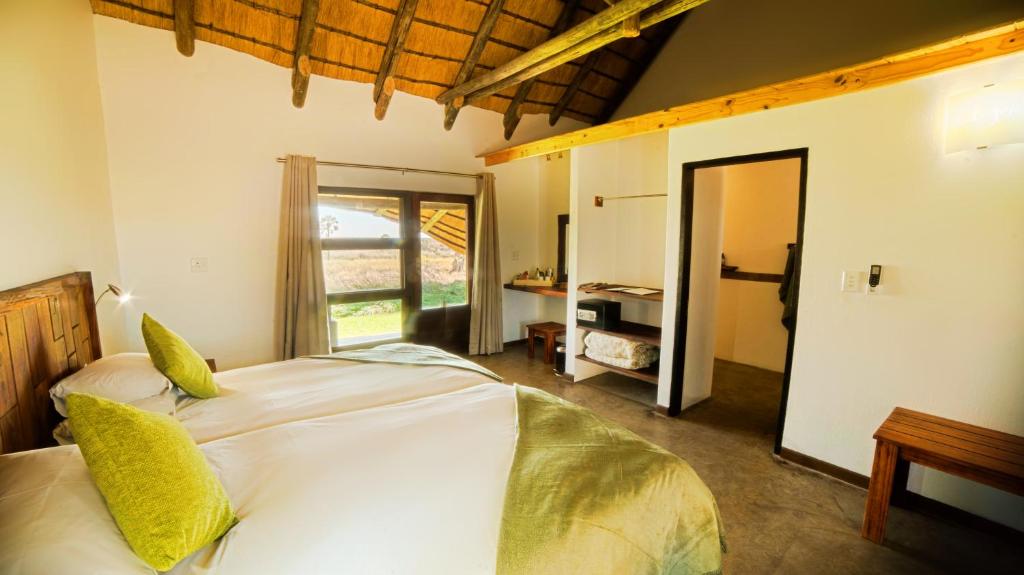 a bedroom with a large white bed with yellow pillows at Palmwag Lodge in Palm