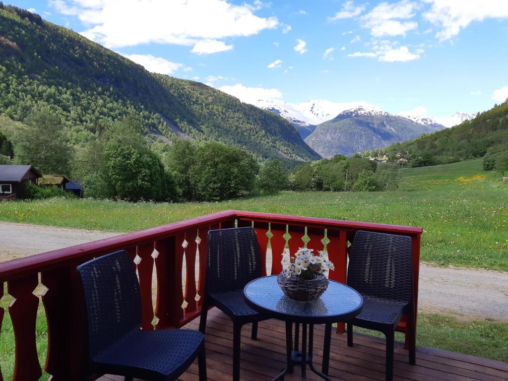 una mesa y sillas en un balcón con montañas en Eidsdal Camping og Feriehus en Eidsdal